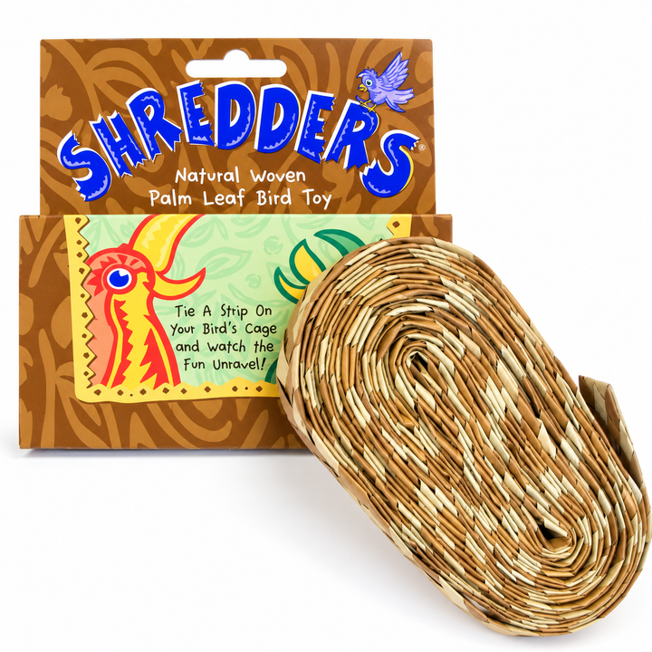 A rolled natural woven palm leaf bird toy next to its retail packaging, featuring a brown cardboard box with blue 'SHREDDERS' branding and colorful bird illustrations- Planet Pleasures Straight Natural Shredders - Small